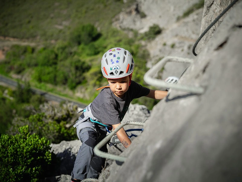 Enfant grimpant sur une paroi équipée lors d’une sortie Via Ferrata famille La Pichona à Saint-Paul-de-Fenouillet.