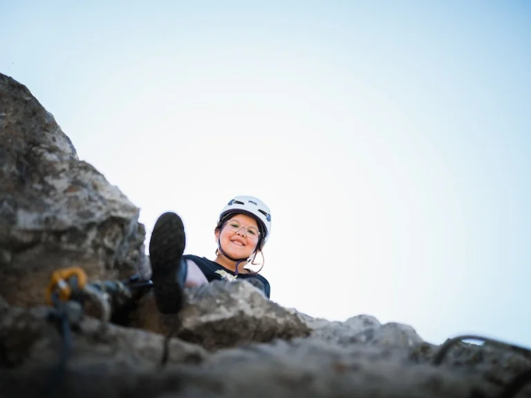 Jeune participante équipée souriante au sommet d’un passage de la Via Ferrata La Pichona à Saint-Paul-de-Fenouillet.