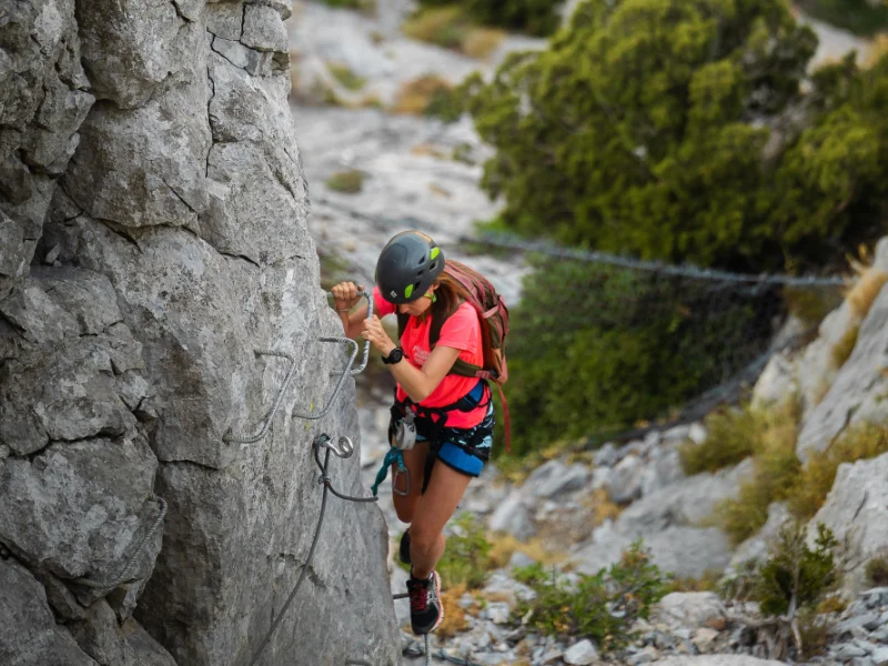 Jeune femme grimpant sur une paroi équipée lors de la Via Ferrata sportive La Panoramique à Saint-Paul-de-Fenouillet.