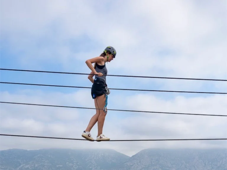 Participante traversant un pont de singe sur la Via Ferrata sportive La Panoramique à Saint-Paul-de-Fenouillet.