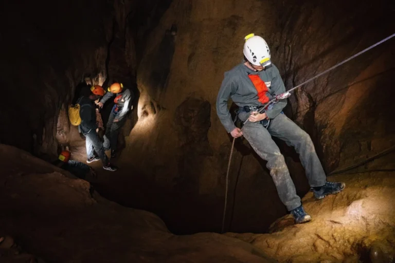 Spéléologue descendant en rappel dans une grotte lors d’une sortie spéléologie dans les gorges de Galamus