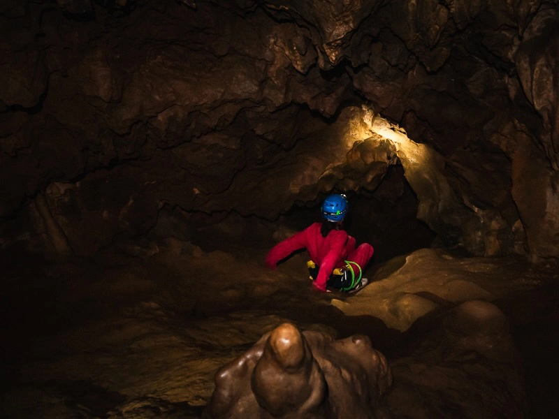 Participant explorant une galerie souterraine lors d’une sortie spéléologie dans les grottes de Galamus dans les Pyrénées-Orientales