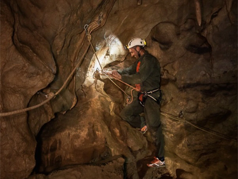 Spéléologue progressant sur corde dans une grotte des gorges de Galamus lors d’une sortie spéléologie dans les Pyrénées-Orientales