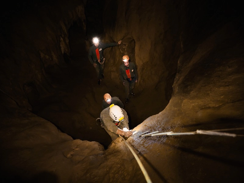 Spéléologue remontant une échelle spéléo dans un puits de grotte lors d’une sortie spéléologie dans les Pyrénées-Orientales