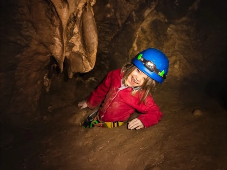Enfant explorant un passage de grotte lors d’une sortie spéléologie dans le massif de Galamus dans les Pyrénées-Orientales