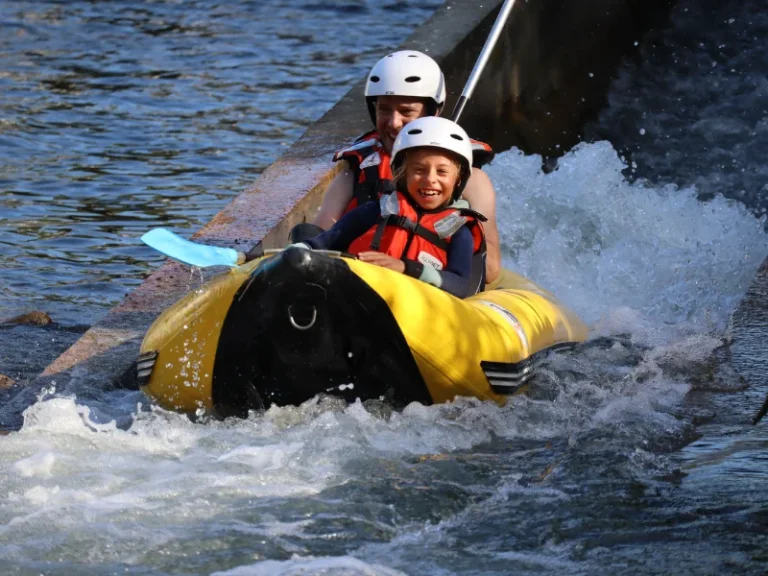 parent et enfant en canoraft franchissant une petite vague sur la rivière Aude près d’Axat dans les Pyrénées audoises