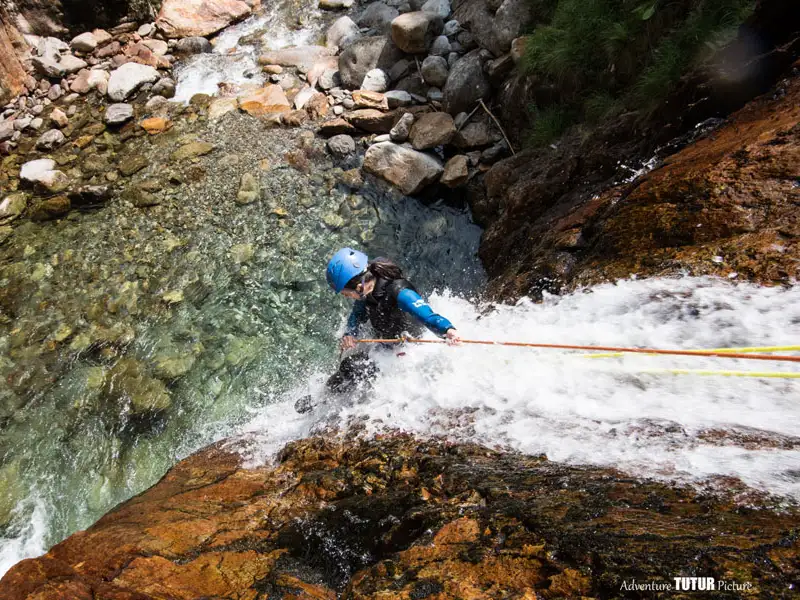 Participant descendant en rappel dans une cascade du canyon de l’Artigue en Ariège avec une vasque d’eau claire dans la vallée de Vicdessos
