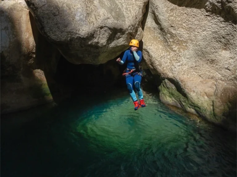 Participant sautant dans une vasque turquoise lors d’une sortie canyoning dans les gorges de Galamus près de Saint-Paul-de-Fenouillet dans les Pyrénées-Orientales