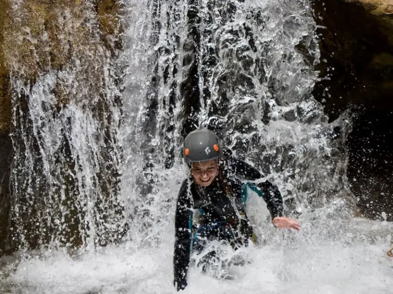 Participante passant sous une cascade lors d’une sortie canyoning dans le canyon de Galamus près de Saint-Paul-de-Fenouillet