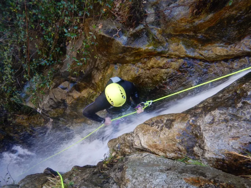 Pratiquant descendant en rappel dans une cascade étroite du canyon d’eau chaude de Thuès lors d’une sortie canyoning hivernale dans les Pyrénées-Orientales