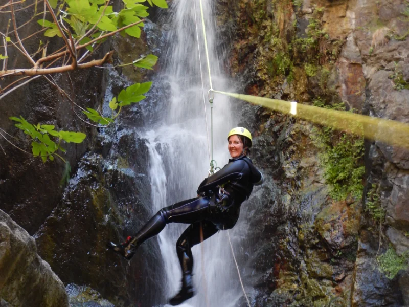 Participant descendant en rappel dans une cascade du canyon d’eau chaude de Thuès lors d’une sortie canyoning hivernale dans les Pyrénées-Orientales près de Font-Romeu