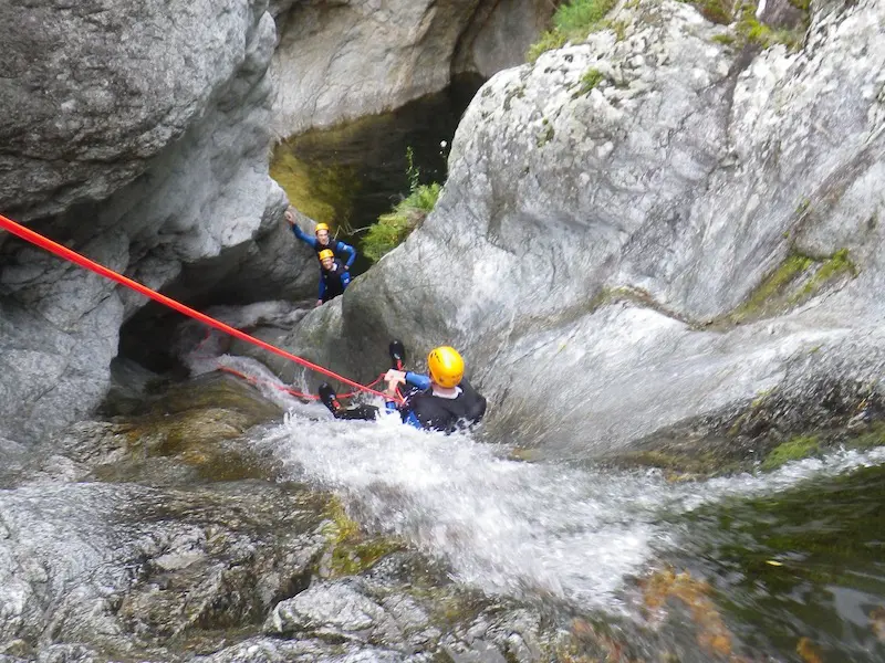 Groupe de participants réalisant une descente en rappel dans une cascade du canyon du Mas Calsan lors d’une sortie canyoning dans les Pyrénées-Orientales près de Céret.