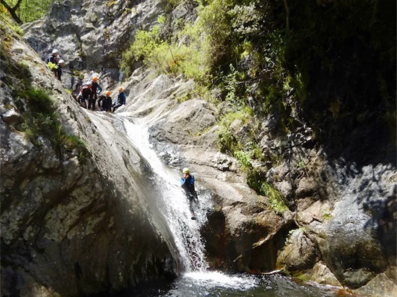 Participant descendant un toboggan naturel dans le canyon du Mas Calsan lors d’une sortie canyoning près de Céret dans les Pyrénées-Orientales.