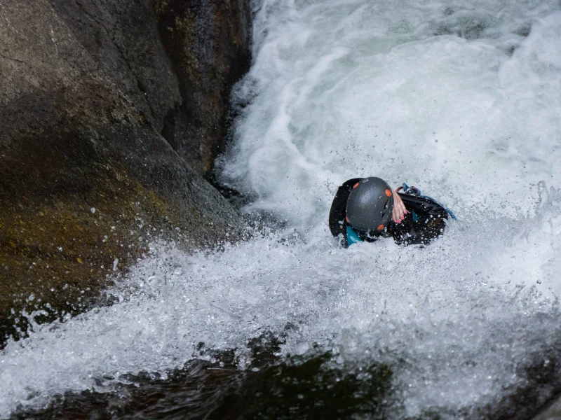Participant descendant un toboggan naturel sous cascade dans le canyon du Llech lors d’une sortie de canyoning sportif dans les Pyrénées-Orientales