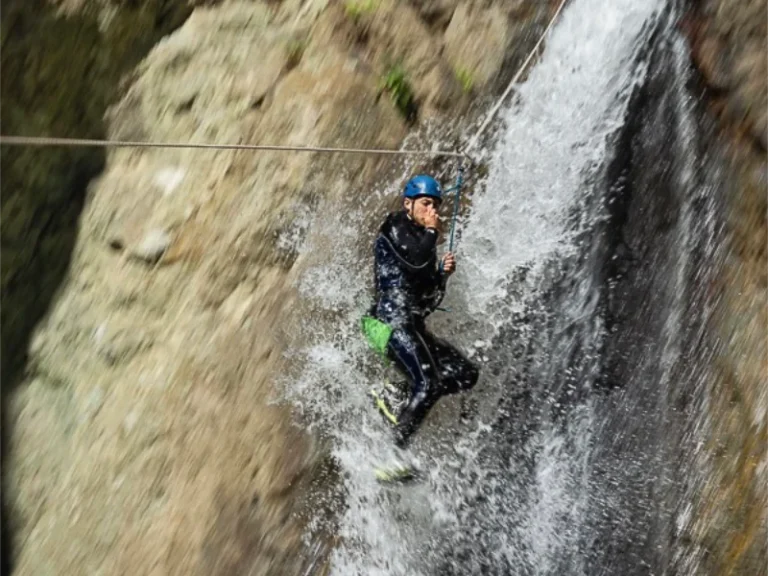 Participant traversant une cascade en tyrolienne dans le canyon du Llech lors d’une sortie de canyoning dans les Pyrénées-Orientales près de Prades