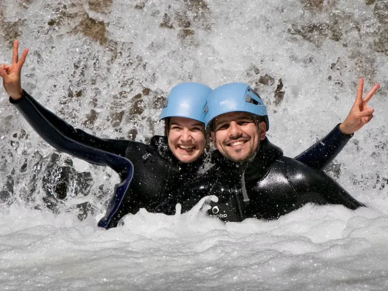Couple souriant en canyoning sous une cascade dans les Pyrénées-Orientales