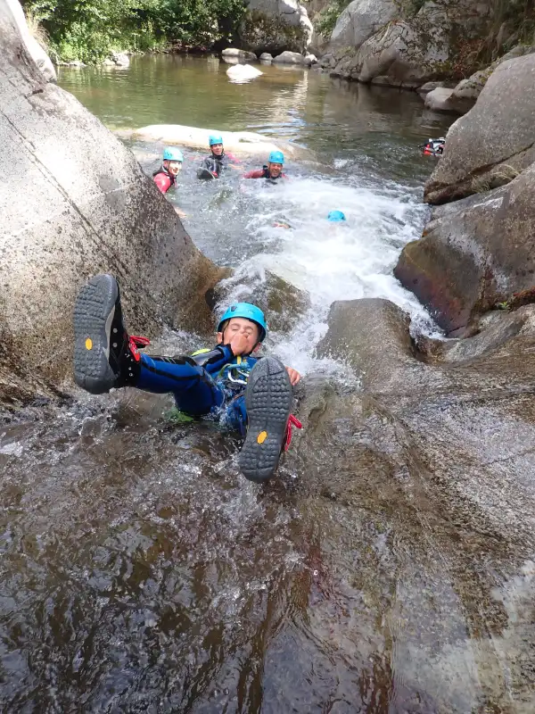 Enfant descendant un toboggan naturel lors d'une sortie canyoning dans le canyon de Molitg-les-Bains près de Prades dans les Pyrénées-Orientales