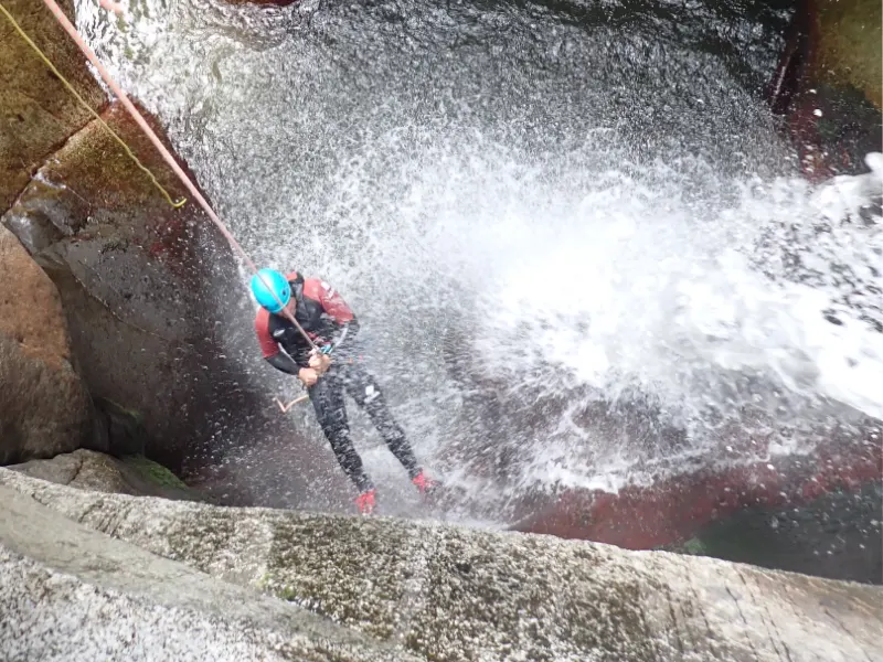 Participant réalisant une descente en rappel sous une cascade dans le canyon de Molitg-les-Bains près de Prades