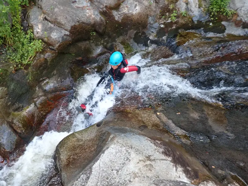 Participant glissant dans un toboggan naturel lors d'une sortie canyoning famille à Molitg-les-Bains